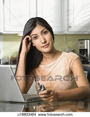 Picture - Young Woman With Laptop and Holding Cellphone. Fotosearch
