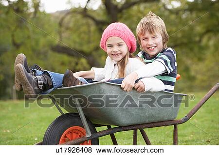 Stock Photo - Boy And Girl Sitting In Wheelbarrow. Fotosearch