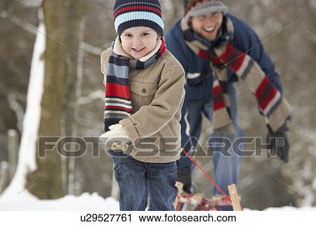 Stock Image - Children Pulling Sledge Through Winter Landscape. Fotosearch