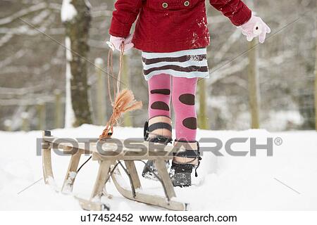 Stock Image - Close Up Of Girl Pulling Sledge Through Winter Landscape. Fotosearch