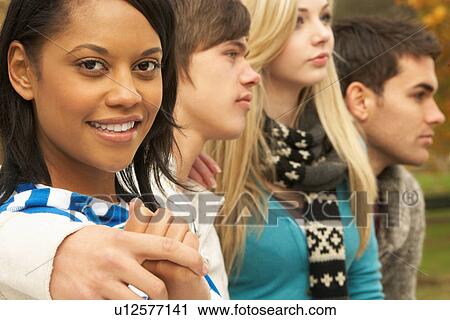 Stock Image - Close Up Of Group Of Four Teenage Friends In Autumn Woodland. Fotosearch