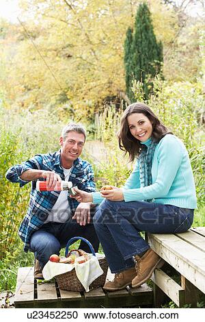 Stock Image - Couple Enjoying Picnic Outdoors In Autumn Woodland. Fotosearch