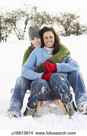Picture - Couple Sledging Through Snowy Woodland. Fotosearch