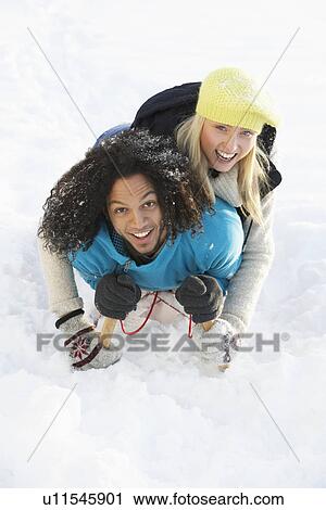 Stock Image - Couple Sledging Through Snowy Woodland. Fotosearch
