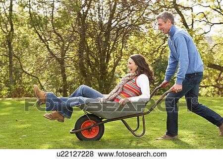 Couple With Man Giving Woman Ride In Wheelbarrow View Large Photo Image Stock Photo - Couple With Man Giving Woman Ride In Wheelbarrow. Fotosearch