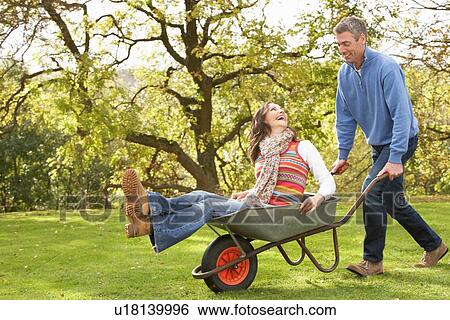 Stock Photograph - Couple With Man Giving Woman Ride In Wheelbarrow. Fotosearch