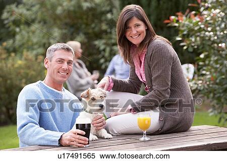 Couple With Pet Dog Outdoors Enjoying Drink In Pub Garden View Large Photo Image Stock Photography - Couple With Pet Dog Outdoors Enjoying Drink In Pub Garden. Fotosearch