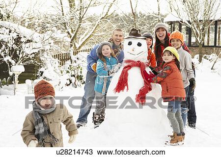 Stock Image - Family Building Snowman In Garden. Fotosearch