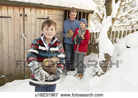 Stock Photo - Family Collecting Logs From Wooden Store In Snow. Fotosearch