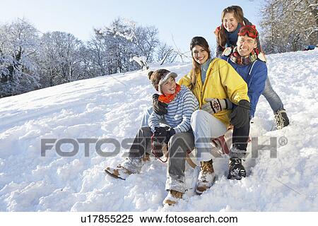 Stock Photography - Family Enjoying Sledging Down Snowy Hill. Fotosearch