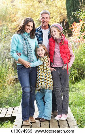 Stock Image - Family Group Standing Outdoors On Wooden Walkway In Autumn Landscape. Fotosearch