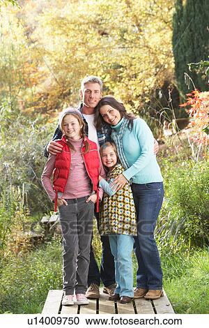Stock Image - Family Group Standing Outdoors On Wooden Walkway In Autumn Landscape. Fotosearch