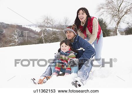 Stock Image - Family In Snow Riding On Sledge. Fotosearch