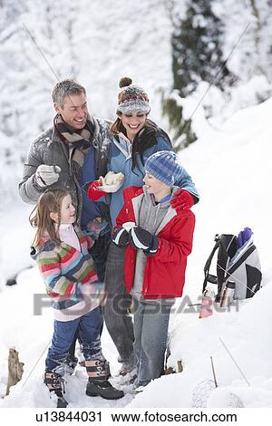Stock Image - Family Stopping For Hot Drink And Snack On Walk Through Snowy Landscape. Fotosearch