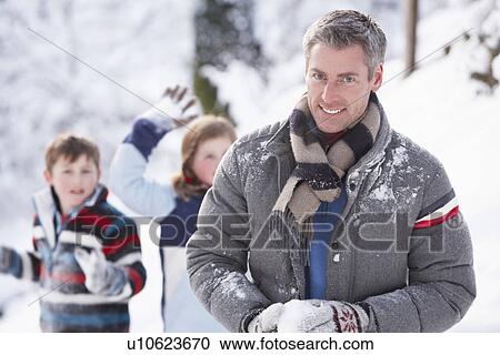 Stock Image - Father And Children Having Snowball Fight In Winter Landscape. Fotosearch