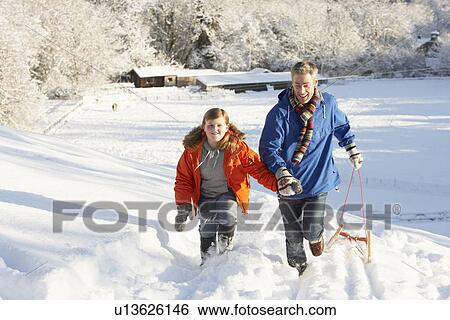 Stock Photograph - Father And Son Pulling Sledge Up Snowy Hill. Fotosearch