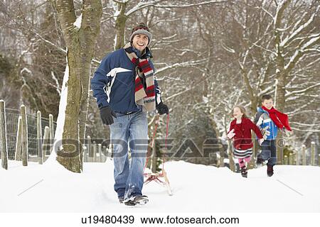 Stock Photo - Father Pulling Children On Sledge Through Winter Landscape. Fotosearch