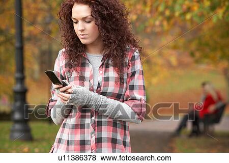 Stock Photo - Frustrated Teenage Girl Making Mobile Phone Call In Autumn Landscape. Fotosearch