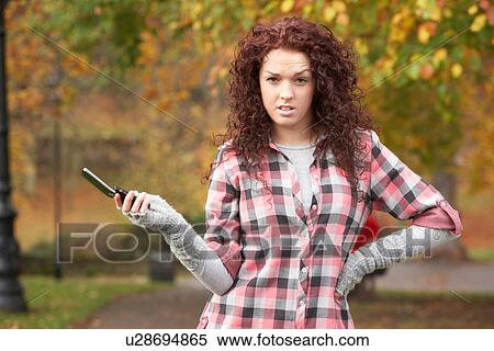 Stock Photography - Frustrated Teenage Girl Making Mobile Phone Call In Autumn Landscape. Fotosearch