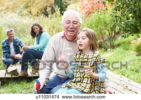 Picture - Grandfather And Granddaughter Blowing Bubbles On Family Picnic. Fotosearch