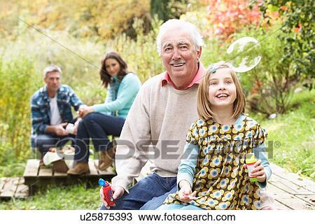 Grandfather And Granddaughter Blowing Bubbles On Family Picnic View Large Photo Image Stock Image - Grandfather And Granddaughter Blowing Bubbles On Family Picnic. Fotosearch
