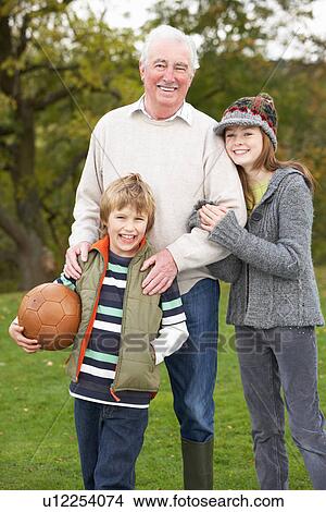 Picture - Grandfather With Grandchildren Holding Football Outside. Fotosearch
