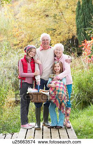 Picture - Grandparents With Grandchildren Carrying Picnic Basket By Autumn Woodland. Fotosearch
