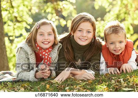 Stock Image - Group Of 3 Children Realxing Outdoors In Autumn Landscape. Fotosearch
