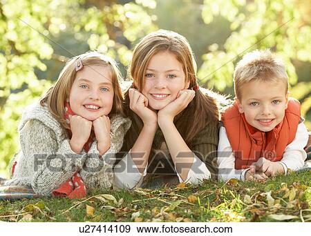 Stock Photo - Group Of 3 Children Realxing Outdoors In Autumn Landscape. Fotosearch