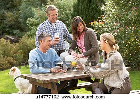 Stock Image - Group Of Friends Outdoors Enjoying Drink In Pub Garden. Fotosearch