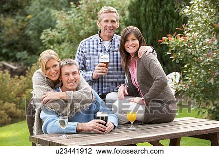 Stock Image - Group Of Friends Outdoors Enjoying Drink In Pub Garden. Fotosearch