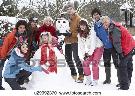 Stock Image - Group Of Teenage Friends Building Snowman In Garden. Fotosearch