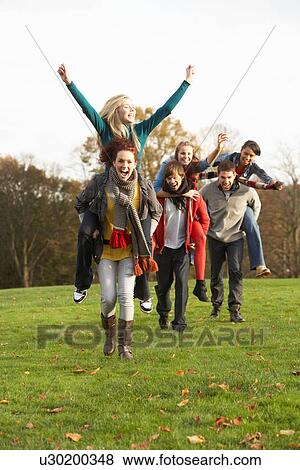 Group Of Teenage Friends Having Piggyback Rides In Autumn Landscape View Large Photo Image Stock Photo - Group Of Teenage Friends Having Piggyback Rides In Autumn Landscape. Fotosearch