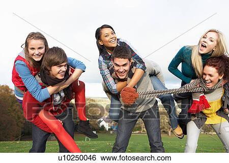 Stock Photograph - Group Of Teenage Friends Having Piggyback Rides In Autumn Landscape. Fotosearch