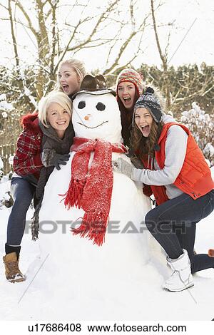 Stock Photo - Group Of Teenage Girls Building Snowman. Fotosearch
