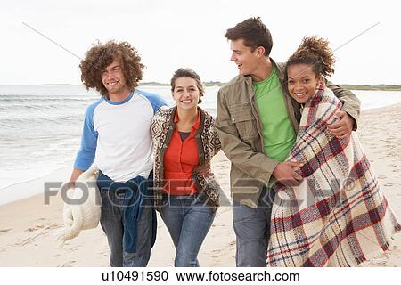 Stock Image - Group Of Young Friends Walking Along Autumn Shoreline. Fotosearch