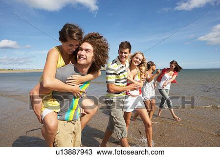 Stock Image - Group Of Young Friends Walking Along Summer Shoreline. Fotosearch