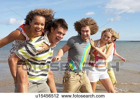 Stock Image - Group Of Young Friends Walking Along Summer Shoreline. Fotosearch