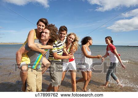 Stock Image - Group Of Young Friends Walking Along Summer Shoreline. Fotosearch