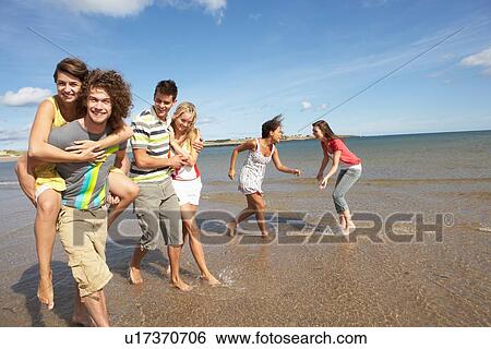 Stock Photograph - Group Of Young Friends Walking Along Summer Shoreline. Fotosearch