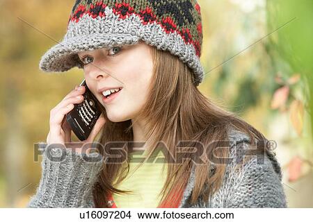 Picture - Head And Shoulders Of Young Girl In Autumn Woodland Using Mobile Phone. Fotosearch