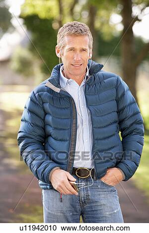 Stock Image - Man Listening To MP3 Whilst Walking In Autumn Park. Fotosearch