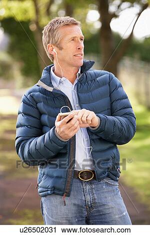 Man Listening To MP3 Whilst Walking In Autumn Park View Large Photo Image Stock Image - Man Listening To MP3 Whilst Walking In Autumn Park. Fotosearch