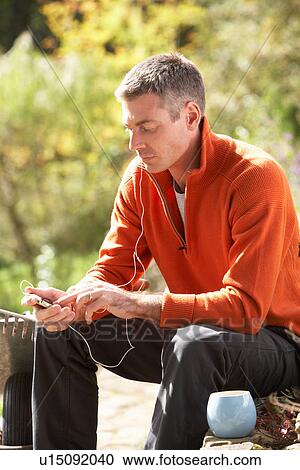 Man Outdoors Listening To MP3 Player Whilst On Break From Gardening View Large Photo Image Stock Image - Man Outdoors Listening To MP3 Player Whilst On Break From Gardening. Fotosearch