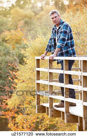 Man Standing On Wooden Balcony Overlooking Autumn Woodland View Large Photo Image Stock Image - Man Standing On Wooden Balcony Overlooking Autumn Woodland. Fotosearch