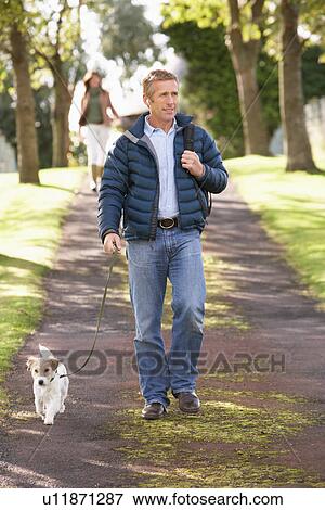 Stock Photo - Man Walking Dog Outdoors In Autumn Park. Fotosearch