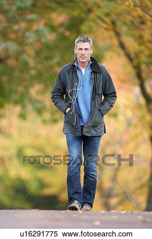 Stock Photography - Man Walking Through Autumn Park Listening to MP3 Player. Fotosearch
