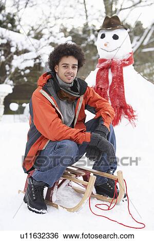Stock Photograph - Man With Sledge Next To Snowman. Fotosearch