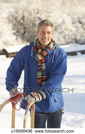 Middle Aged Man Standing In Snowy Landscape Holding Sledge View Large Photo Image Stock Photograph - Middle Aged Man Standing In Snowy Landscape Holding Sledge. Fotosearch