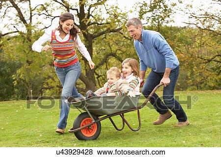 Parents Giving Children Ride In Wheelbarrow View Large Photo Image Stock Photo - Parents Giving Children Ride In Wheelbarrow. Fotosearch
